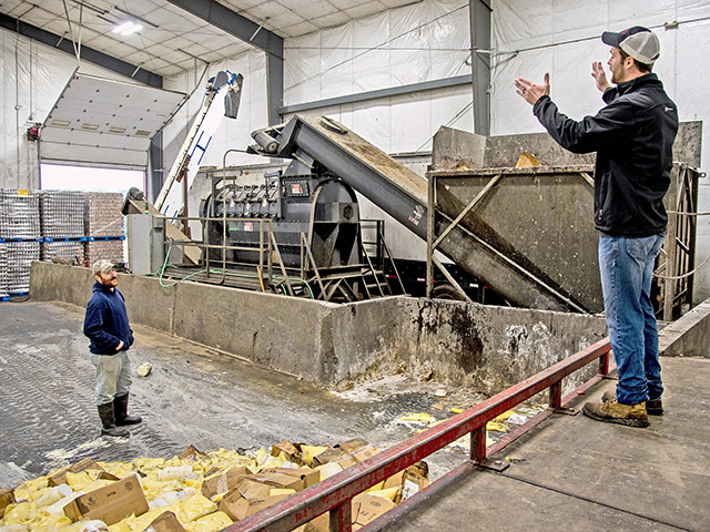 Brett Reinford (right) talks with worker Dennis Walton in the â€œdepackagingâ€� building, where food waste is separated from its packaging and blended in the anaerobic digester with the manure, Image by Tom Gralish